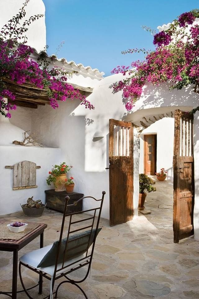 Sunny and charming Mediterranean-style patio courtyard, covered in blooming pink bougainvillea.