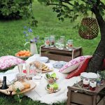 Beautiful picnic spread with wood storage crate tables,vhll hanging lantern in tree, and pillows for seating.