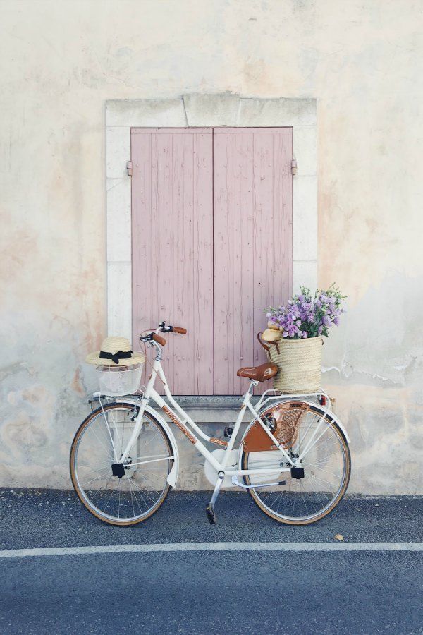 Charming bicycle with French market basket (Vivi et Margot) of flowers and pink shutters on window. Vivi et Margot. Come be inspired by more French farmhouse design inspiration on Hello Lovely. #vivietmargot #bicycle #pink 