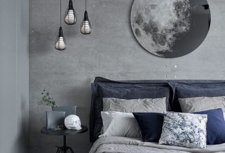 a chic grey and navy bedding set plus a blue rug enliven the grey bedroom