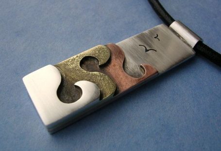 En argent massif, laiton et cuivre et doté d’un design de vague océan simple. Il mesure environ 1cm par 3,5 cm. Le fond est fait d’argent et dispose de 2 mouettes minuscules, suivies par des couches de cuivre, laiton et argent des vagues. Le pendentif ensemble est ensuite oxydé et