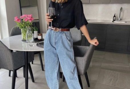 Chica usando playera negra, con mom jeans de mezclilla clara y sandalias de color negro